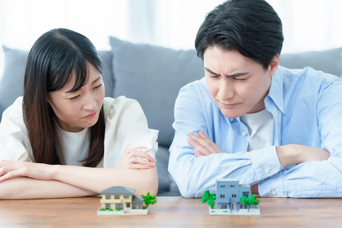 2つのおうちの模型を前に考え込むご夫婦