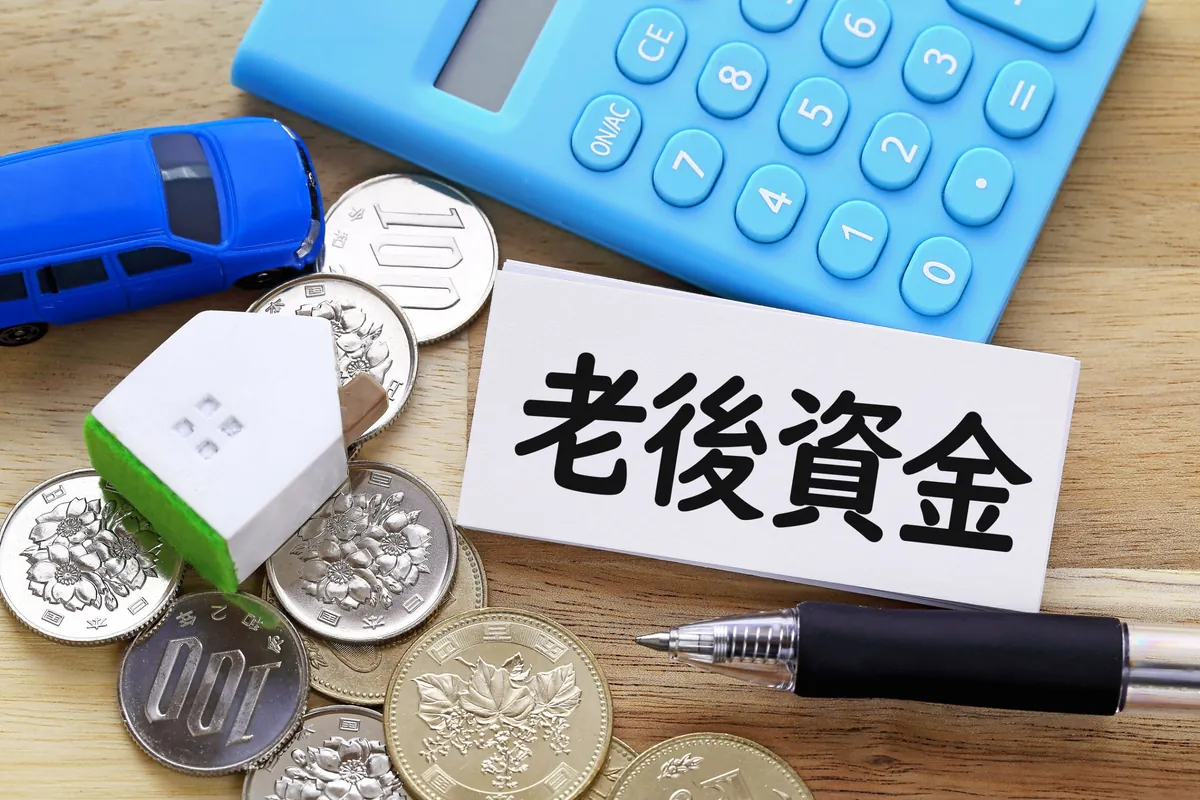 老後資金と書かれたカードと電卓、おうちの模型