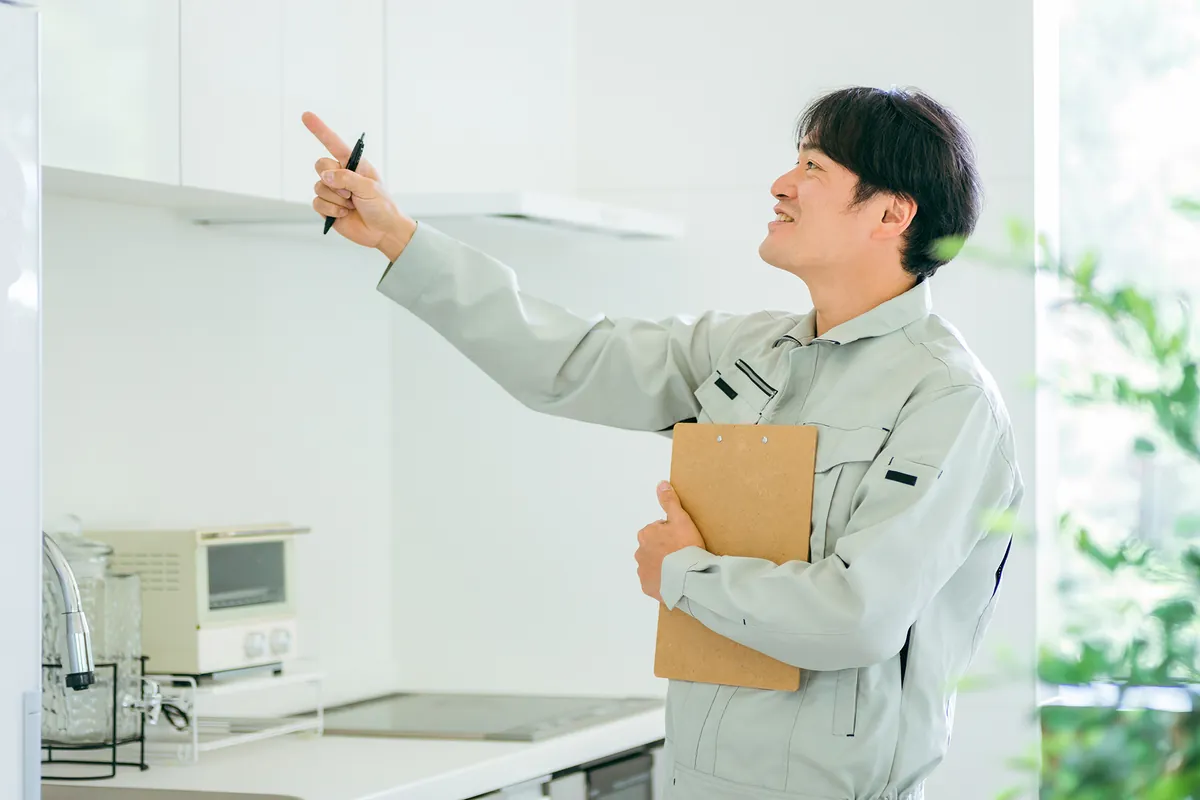 キッチンの吊り戸棚を指さして確かめるスタッフ