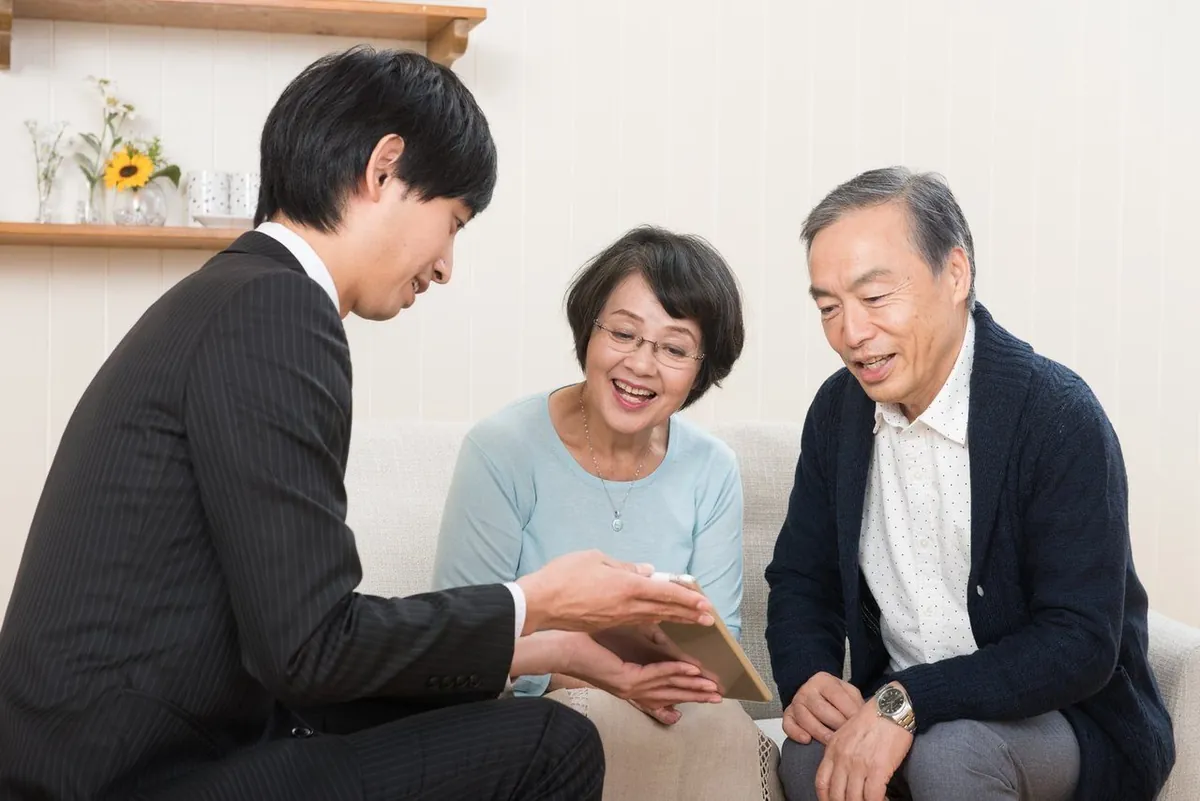 スタッフの説明をソファで聞く年配のご夫婦